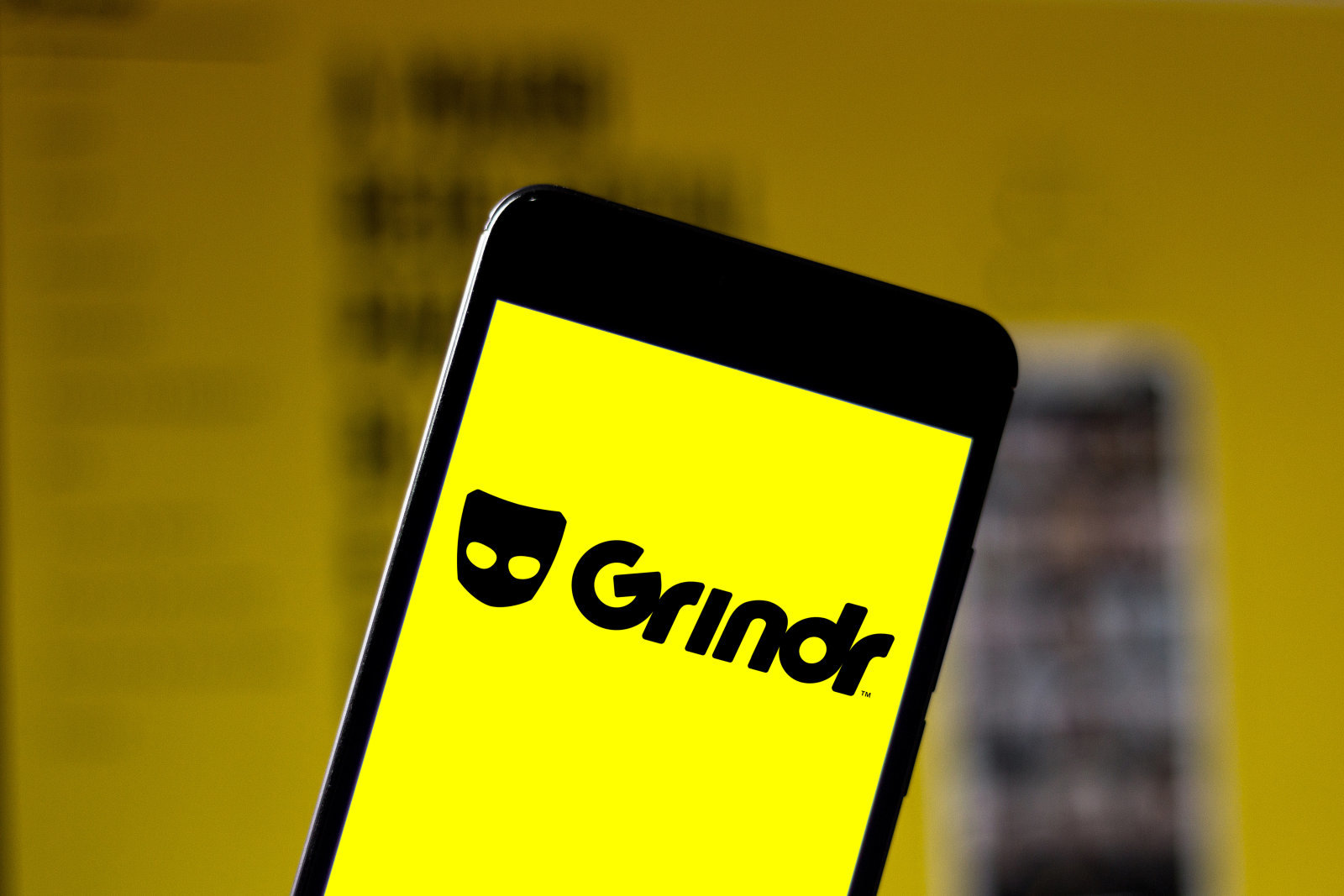 In this photo illustration a Grindr logo seen displayed on a